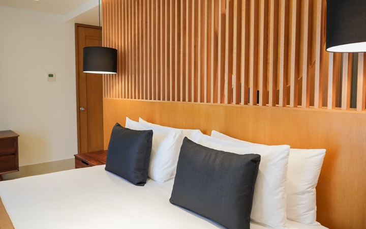 Close-up of the Scenic Studio headboard framing a King-size bed, accompanied by a custom nightstand and dual hanging ceiling lamps at Kadun Hotel Boutique.