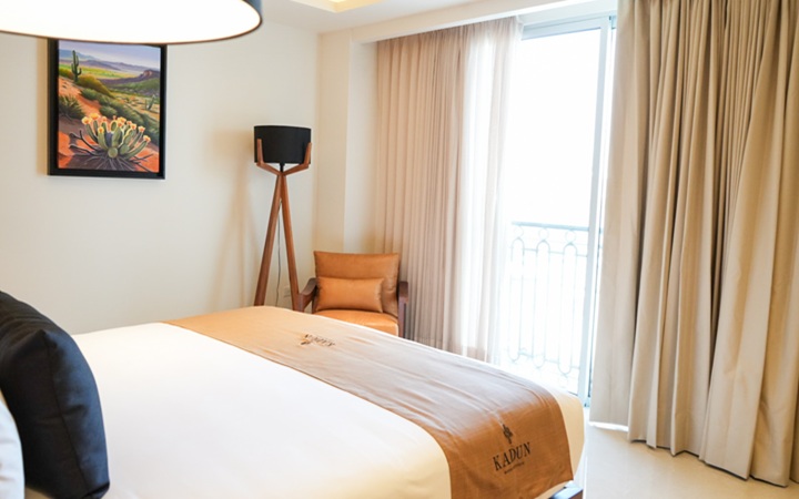 Boutique Scenic Studio suite featuring a private balcony, a modern accent lounge chair, and panoramic views at Kadun Hotel Boutique.