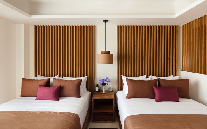 Sophisticated design of the Studio room featuring two plush double beds with a central wooden nightstand and custom reading lamp at Kadun Hotel Boutique.