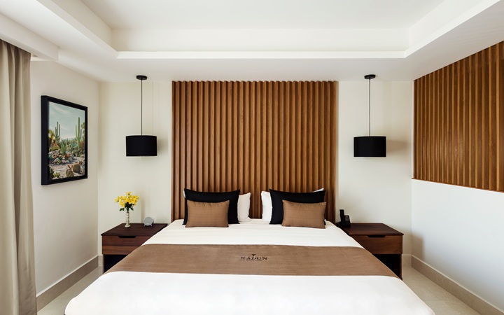 Minimalist luxury Studio suite featuring a plush King-size bed flanked by symmetrical wooden nightstands and elegant designer lamps at Kadun Hotel Boutique.