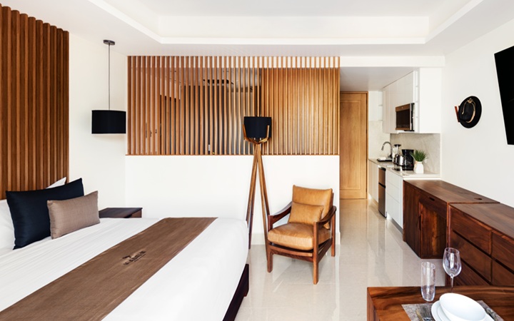 Panoramic view of the luxury Studio suite featuring a fully equipped kitchenette, a dining table, a plush King-size bed, and a dedicated work desk with chair at Kadun Hotel Boutique.