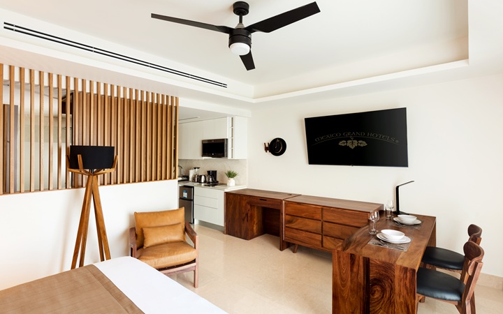 Sophisticated dining and workspace setup inside the luxury suite, showcasing a minimalist dining table, a dedicated work desk with chair, and a smart TV at Kadun Hotel Boutique.