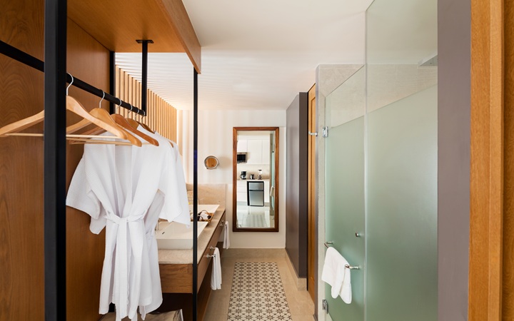 Luxury bathroom suite showcasing a three-fixture layout with separate independent washbasin vanities, a glass-enclosed walk-in shower, and an isolated water closet at Kadun Hotel Boutique.